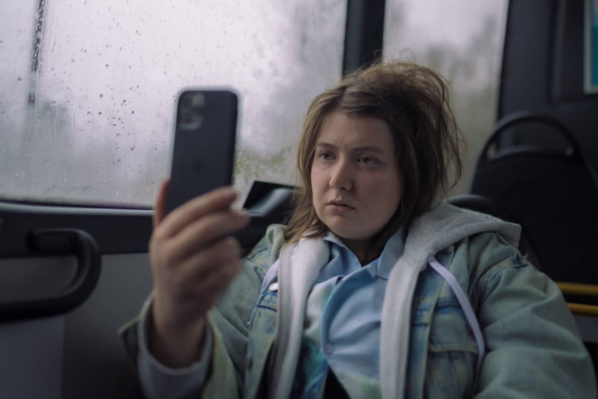 Kvinne med morratryne som bruker BankID-app på bussen