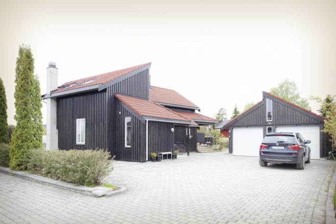 Oppkjørsel med svart hus, garasje og bil. foto